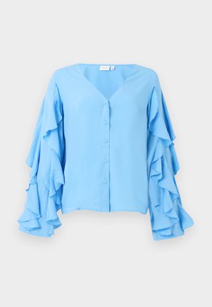 Chemisier bleu clair avec un décolleté en V, doté de fermetures à boutons et de manches longues ornées de volants superposés. Texture de tissu douce.