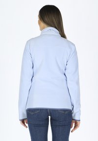 Helle blaue Fleecejacke mit hohem Kragen, kontrastierender Borte und Nahtdetails, kombiniert mit dunklen Jeans; Rückansicht, ohne sichtbare Beschläge.