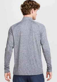 Langarm sportshirt van heather grijs stof. Heeft een schuilkraag, een zachte textuur en raglanmouwen.