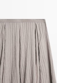 Grey pleated skirt with vertical stripes, featuring a wide waistband and textured fabric for a structured appearance.