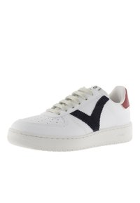Zapatilla de cuero blanca con un swoosh de ante azul marino, cordones gris claro y un acento en el talón rojo. Presenta una suela de goma texturizada y una puntera perforada.