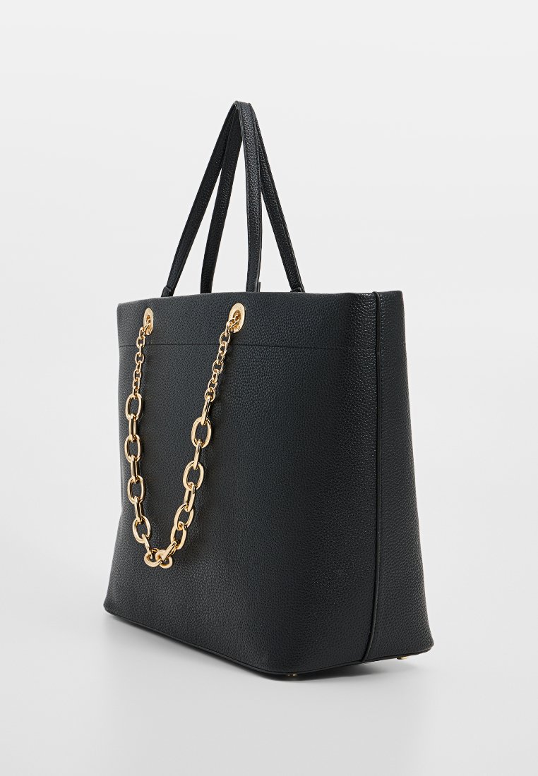 Sac à main en cuir noir avec un fini texturé, présentant des accents en chaîne dorée et deux anses. Forme rectangulaire avec une base plate.