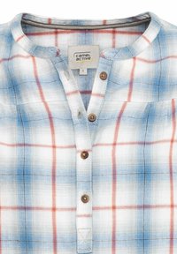 Chemise à carreaux bleu clair et blanc avec des lignes rouges et noires, col rond, et boutons marron sur le devant au centre.