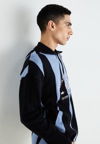 Sort og blå stribet sweater med krave, med strikket tekstur og grafisk print foran. Slim fit-design.