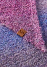 Écharpe en laine texturée violet et rose de forme triangulaire avec une étiquette en cuir marron portant le nom de la marque "mxo by maximo."