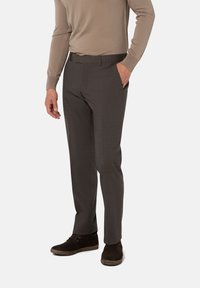 Graue, maßgeschneiderte Hosen mit einer subtilen Textur und schmalem Schnitt. Tragen mit einem beigefarbenen Langarmshirt und braunen Schuhen.
