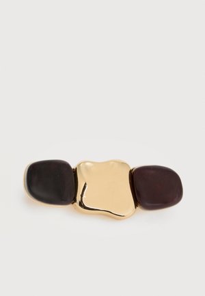 Agrafă de păr cu ton auriu și două pietre rotunjite maro închis pe fiecare parte, pe un fundal alb.