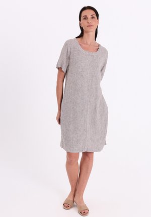 Woman standing wearing a knee-length, short-sleeve gray linen dress and beige open-toe slide sandals against a white background.