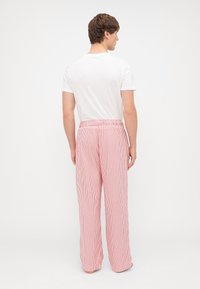 Punase ja valge triibuline pidžaamapüks, millel on elastne vöökoht, laiad sääred ja kerge kangas. Kanda lihtsa valge T-särgi juurde.