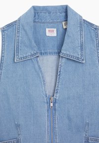 Ljusblå denimväst med bred krage, framdragkedja och två sidofickor. Strukturerad tyg med en något blekt utseende.