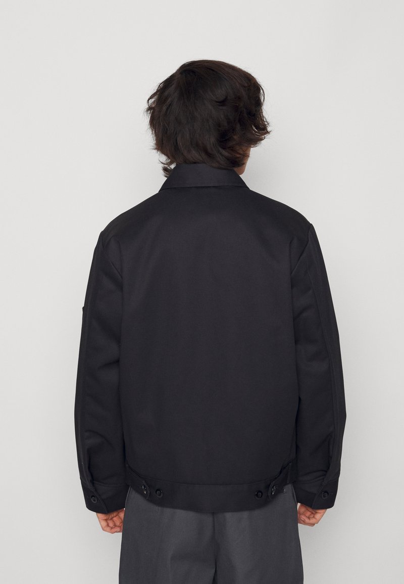 Chaqueta negra con un diseño estructurado, hecha de un tejido suave. Presenta un cuello clásico, puños abotonados y un ajuste entallado en la cintura.