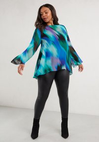 Flowing blue and green abstract print top with bell sleeves; layered design over black leggings and black ankle boots. Smooth texture.