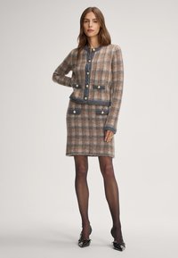 Karierter Tweed-Kleidungsset in Braun- und Grautönen, mit Rundhalsausschnitt, goldenen Knöpfen, zwei aufgesetzten Taschen und taillierter Silhouette.