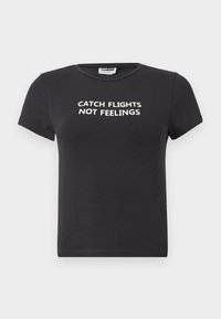 Black cotton t-shirt with short sleeves featuring white text that reads "CATCH FLIGHTS NOT FEELINGS." Classic crew neck design.