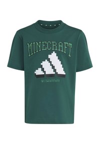T-shirt vert à manches courtes avec le texte "MINECRAFT" et un motif de bloc blanc pixelisé ressemblant au logo Adidas à l'avant.