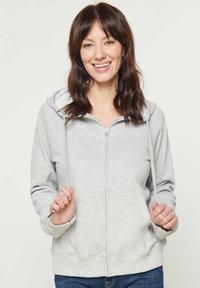 Felpa grigia chiara con zip, cappuccio foderato e lacci. Presenta una zip frontale, maniche lunghe e polsini a coste.