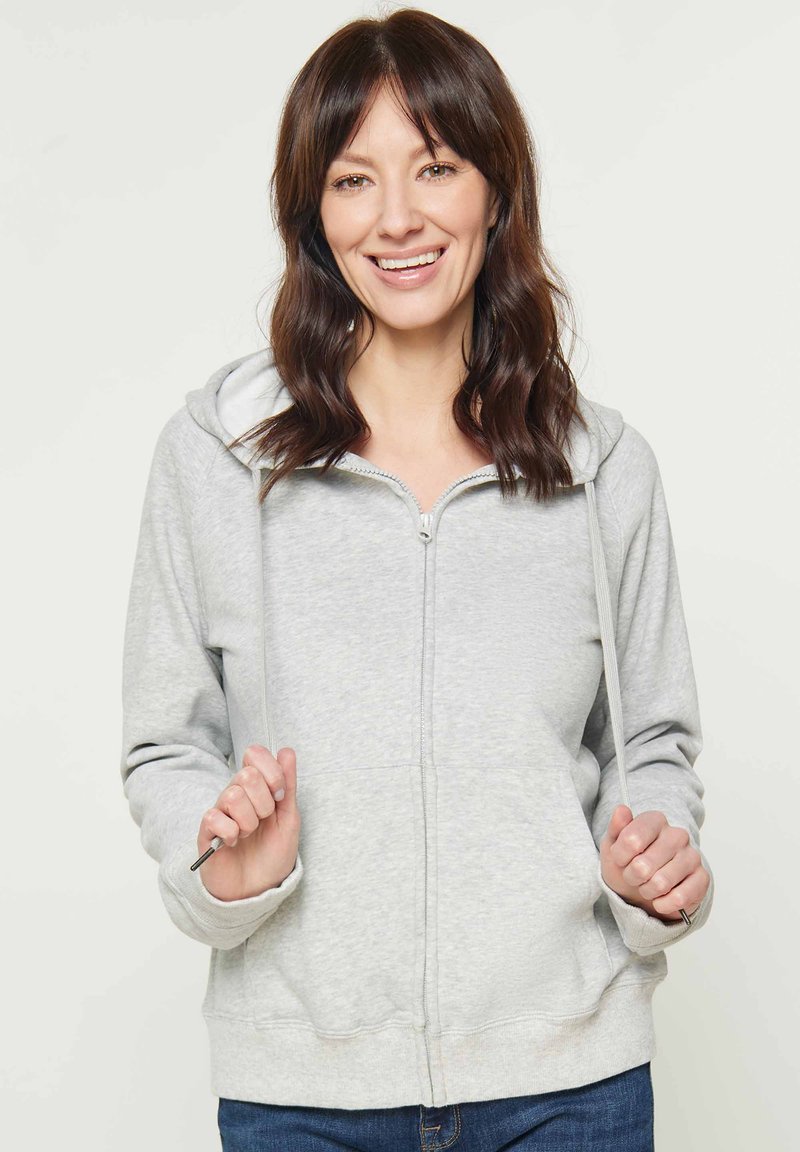 Felpa grigia chiara con zip, cappuccio foderato e lacci. Presenta una zip frontale, maniche lunghe e polsini a coste.