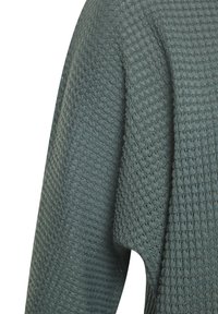 Strickpullover mit Struktur in gedämpftem Grün, ausgestattet mit einem Waffelmuster. Das Material wirkt weich, mit einem lässigen Design und leicht übergroßer Passform.