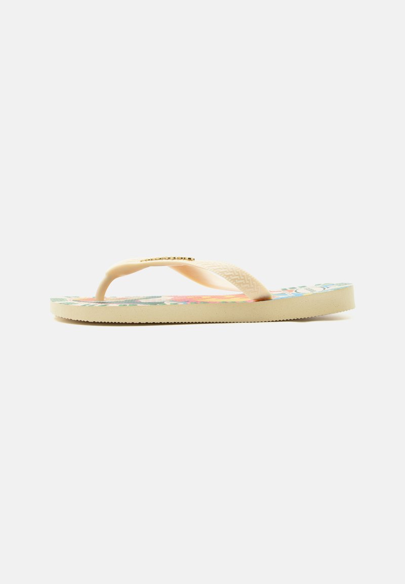 Sandale tong beige avec des brides texturées et un motif floral coloré sur la semelle, vue de côté sur fond blanc.