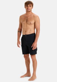 Čierne plavkové šortky s gombíkovým zapínaním a bočnými vreckami. Vyrobené z ľahkej tkaniny, s dĺžkou po kolená a jednoduchou textúrou.