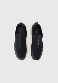 Mornarske slip-on tenisice s gornjim dijelom od teksturirane mreže i kontrastnom kremastom gumom. Imaju petni uvučak i minimalno brendiranje na unutarnjoj strani uloška.