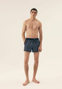 Męskie szorty pływackie w ciemnoniebieskim kolorze z geometrycznym wzorem, elastycznym paskiem w talii, sznurkiem oraz bocznymi kieszeniami. Tekstura materiału wydaje się gładka.