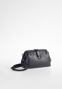 Lederhandtasche in Marineblau mit einer runden Form, Reißverschluss und verstellbarem Trageriemen. Besitzt eine Klappe vorne mit Knopfdetail. Glatte Oberfläche.