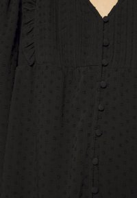 Abito in tessuto nero con texture, caratterizzato da una scollatura a V, dettagli arricciati e chiusura con bottoni nella parte anteriore, con piccoli bottoni rivestiti di tessuto.