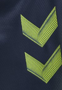 Dwa żółte strzałki w kształcie szewronu z cienkimi czarnymi paskami na ciemnoniebieskim fakturowanym tle tkaniny.