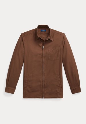 Brown zip-up jacket made of cotton with a collared neck, single chest pocket, and side pockets. Smooth texture and fitted sleeves.