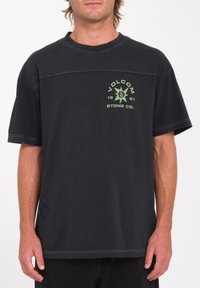 Zwarte katoenen t-shirt met een losse pasvorm. Bevat een groen Volcom-logo op de borst en contrasterende stiknaden langs de naden. Korte mouwen.