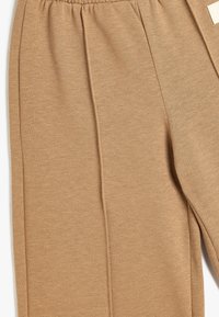 Brune strikbukser med en strækbar talje, lige ben-design og en subtil struktur med en sidesøm detalje.