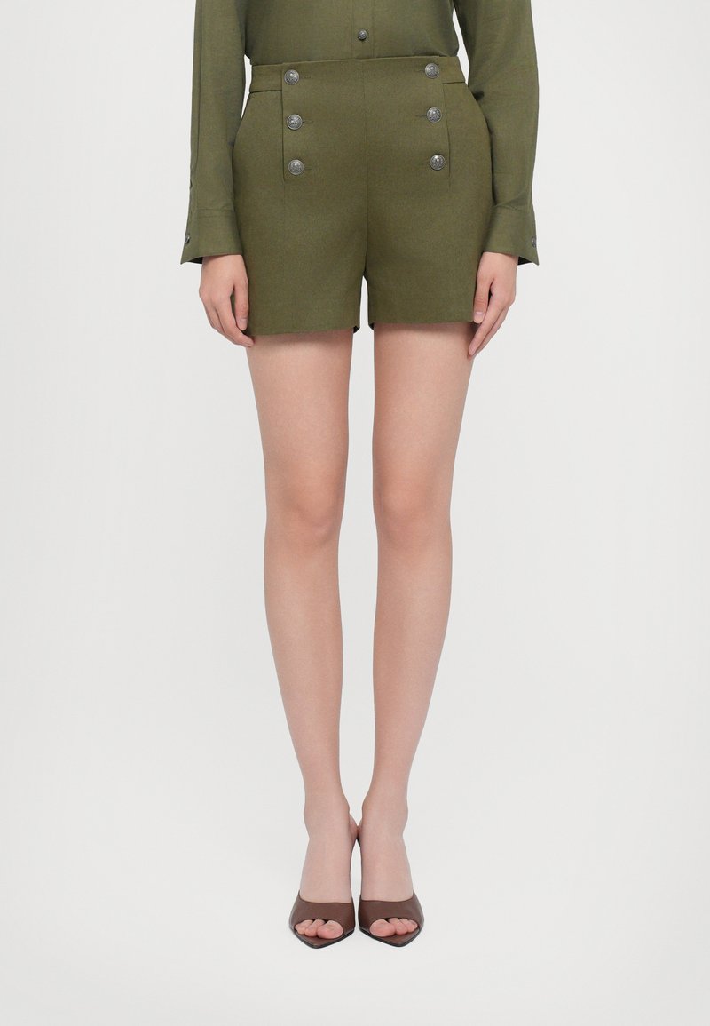 Olivno zeleni šorti s krojem po meri, z dvema vrstama srebrnih gumbov in stranskimi žepi; gladek in strukturiran material.