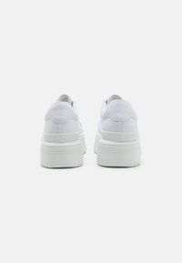 Sneakers bianchi con tomaia in pelle liscia, punta rotonda e suola in gomma spessa e testurizzata. Presentano un design minimalista con cuciture sottili.