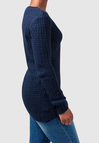 Pull en maille bleu marine avec un motif texturé, col rond et manches longues. La coupe est légèrement ample avec des poignets et un ourlet côtelés.
