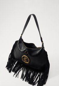 Borsa a mano in pelle nera con dettagli in frange, hardware dorato e un logo circolare prominente sul davanti; tracolla texture.