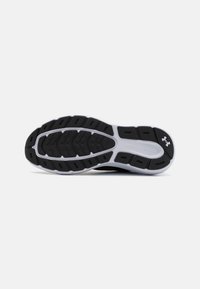 Semelle de chaussure de sport noire en caoutchouc texturé, avec des rainures pour l'adhérence et un intermédiaire blanc. Logo Under Armour près du talon.