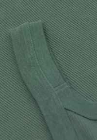 Zielona prążkowana tkanina z teksturowanymi liniami, z gładkim kołnierzykiem i szczegółami przeszyć. Miękki materiał, zbliżenie na część odzieży.