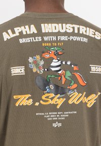 Personaj vulpe îmbrăcat cu o cască și un tricou cu dungi, făcând skateboarding pe o placă de skateboard, ținând un buchet de flori, cu textul "Alpha Industries" deasupra.