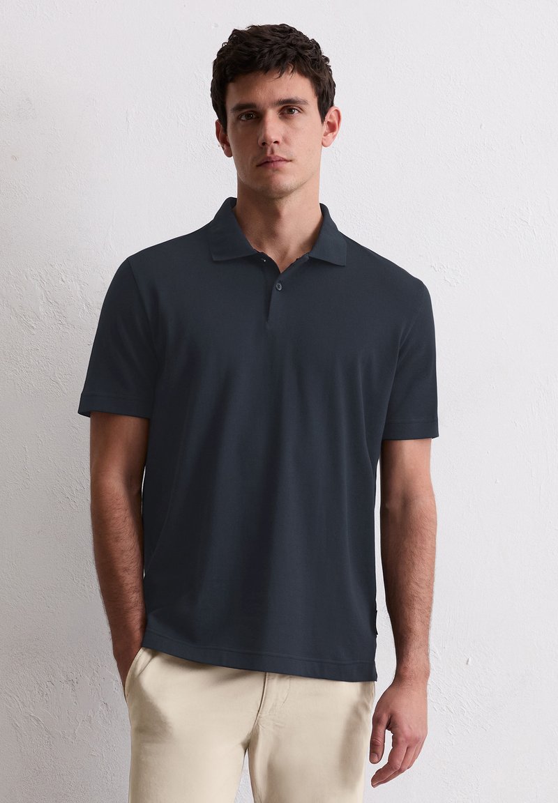 Dunkelblaues Polohemd mit kurzen Ärmeln, aus glattem Stoff gefertigt. Mit Kragen und einer Zwei-Knopf-Leiste, minimalistisches Design.