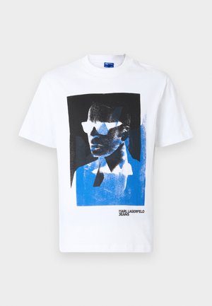 T-shirt bianca in cotone con una stampa grafica blu e nera di un volto con occhiali da sole. Include il testo "KARL LAGERFELD JEANS".