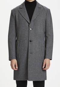 Grau und schwarzer Hahnentrittmantel mit einem einzigen Knopfverschluss, Reverskragen und seitlichen Taschen, aus strukturiertem Stoff für Wärme gefertigt.