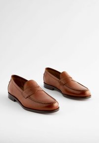 Braune Lederloafers mit glatter Oberfläche, detaillierter Naht und niedrigem Absatz, ausgestattet mit einem erhöhten Dekorstreifen.