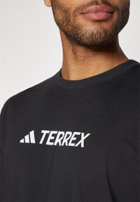 Sort bomulds t-shirt med et hvidt "TERREX" logo og accentgrafik på brystet. Rund halsudskæring med en glat tekstur.