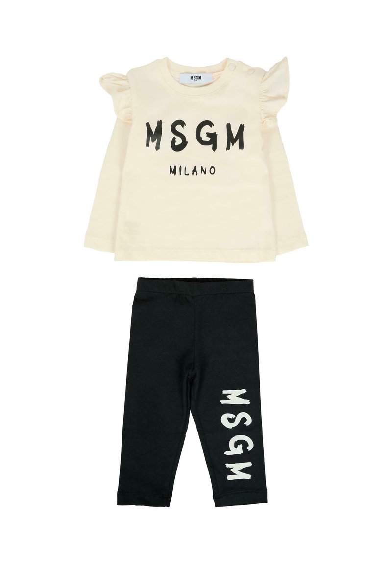 Kremowa bluzka z długim rękawem i falbankami na ramionach, z czarnym napisem "MSGM Milano", zestawiona z czarnymi legginsami z białym napisem "MSGM" na nogawce.