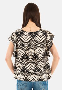 Top a righe bianche e nere con maniche a sbuffo, caratterizzato da un design tie-dye e una vestibilità morbida. Il materiale è leggero e texturizzato.