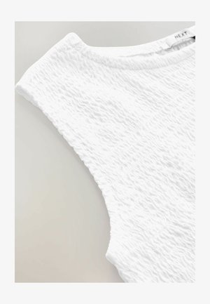 Biely top vyrobený z textúrovaného materiálu s vykrojeným dizajnom. Má široký výstrih a bezrukávový strih, ktorý ukazuje hladký povrch.