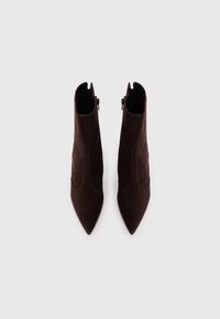 Brown suede ankle boots with pointed toes, side zippers, and minimal stitching details. Smooth texture and sleek design.