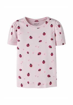 Jasnoróżowa koszulka z krótkim rękawem dla małego dziecka z bufkami na ramionach, ozdobiona rozrzuconymi czerwonymi biedronkami i małymi różowymi serduszkami.