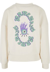 Krémszínű, oversized fazonú pulcsi, amelyen egy kéz grafikája és a zöld és lila köralakú mintában a "KARL X PARIS" felirat található.
